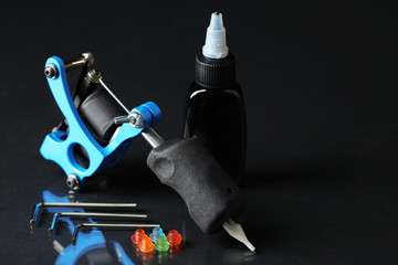 Naklejka premium Tattoo machine and tattoo Supplies, on dark background