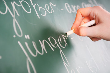 Teacher hand writing grammar sentences on blackboard background