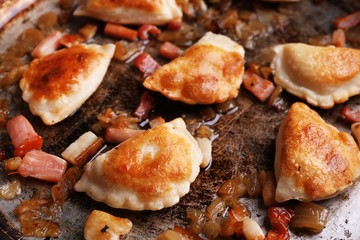 Fried dumplings with onion and bacon in frying pan