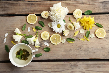 Cup of herbal tea with beautiful flowers, on wooden background