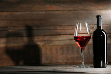 Wine bottle with glass on wooden background