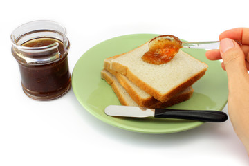 Hand spreads jam on fresh bread