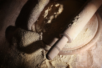 Whole flour with rolling pin on wooden cutting board, closeup