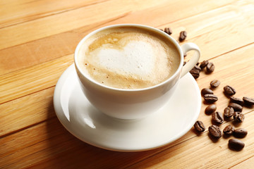 Cup of coffee latte art with grains on wooden background
