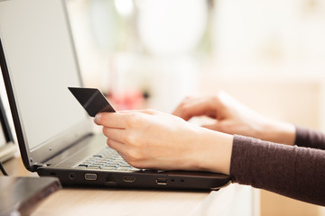 Close-up of woman holding credit card and using laptop