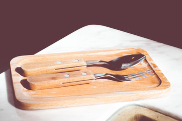 Spoon and fork on wooden tray in coffee shop