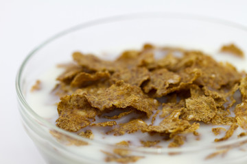Close-up flakes and milk in a glass bowl