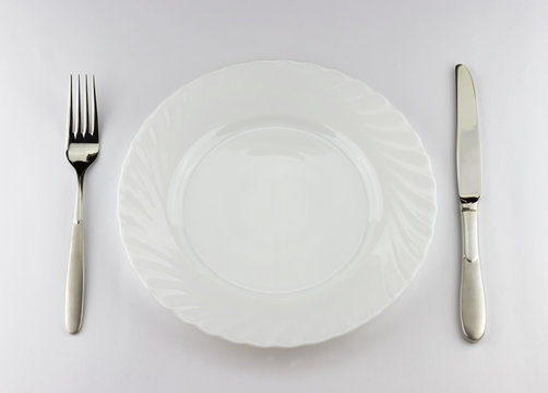 Top view of white plate with silver fork and knife 