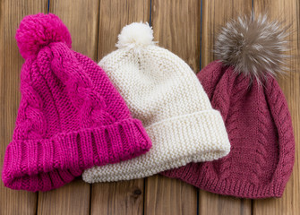 Fototapeta na wymiar Set of colored knit wool hat with pom pom on wooden nackground