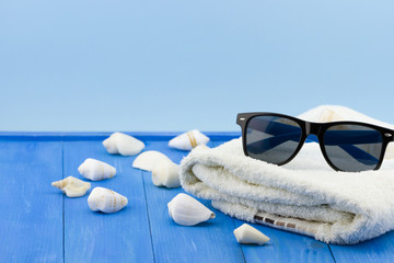 Black sunglasses with shells and white towel 