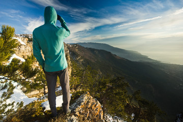 man standing on a cliff in mountains at sunrise