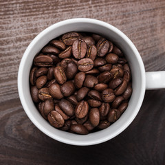 cup of coffee beans on brown wooden background