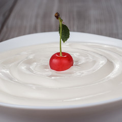 white bowl full of sour cream with cherry