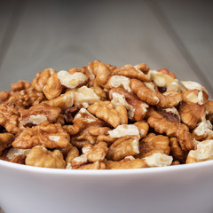 walnuts in the white bowl on wooden table
