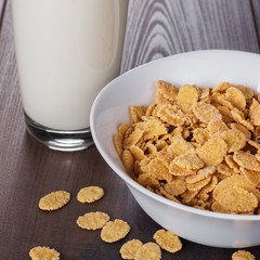 glass of milk and bowl with cornflakes