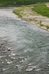 river flow in town and green grass on banks