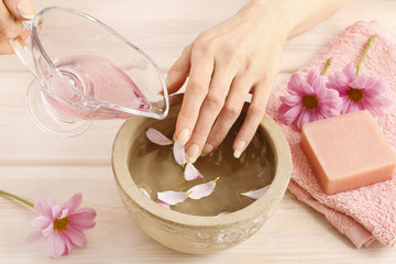 Obraz na płótnie Canvas Hands over ceramic bowl with water and essential oils