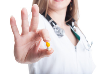 Female doctor offering a yellow vitamin pill