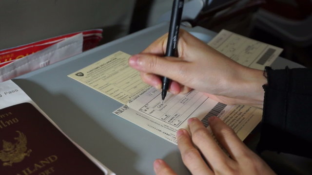 Tourist hand filling custom immigration form writing on plane