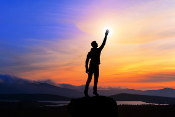 happy man with hand up on sunset background