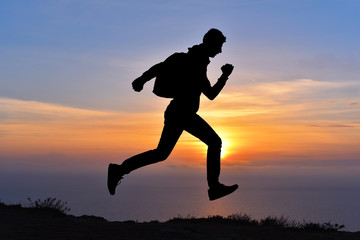 Fototapeta na wymiar Running jumping man above sunset and mountain. Sport nature
