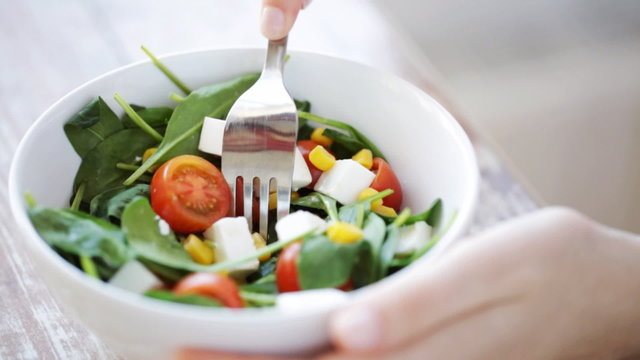 close up of young woman eating salad at home