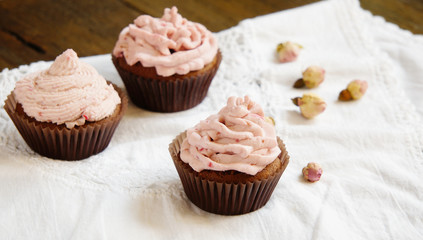 Cupcakes with cream cheese cream with raspberry and dry roses