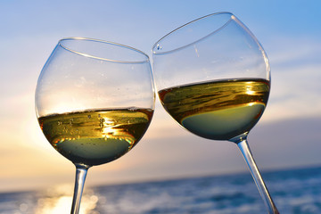 Romantisch glas wijn zittend op het strand bij kleurrijke zonsondergang