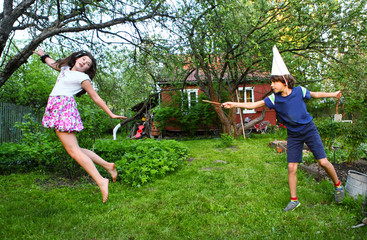 siblings boy and girl play harry potter game with magic stick - obrazy, fototapety, plakaty
