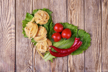 Pasta spaghetti noodles with chili pepper and tomatoes on table