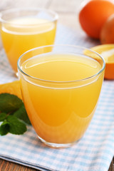 Glasses of orange juice with oranges on wooden table close up