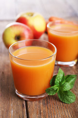 Glasses of juice with apple and carrot on wooden table close up