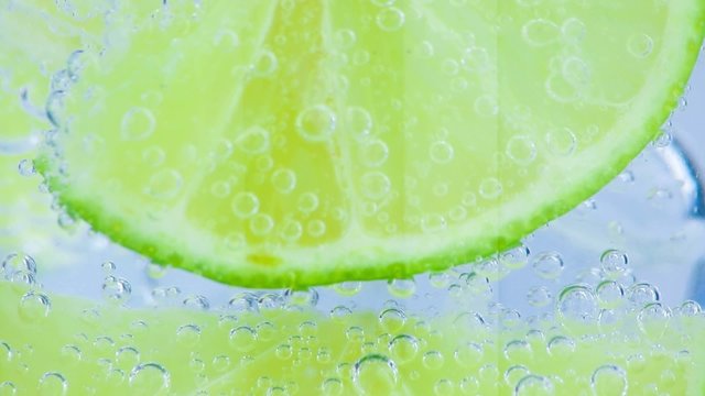close-up of sparkling water with ice and slices lime