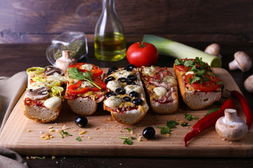 Different sandwiches with vegetables and cheese on cutting board on table close up