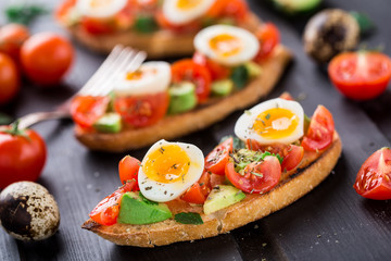 Bruschetta with tomato, avocado and quail egg