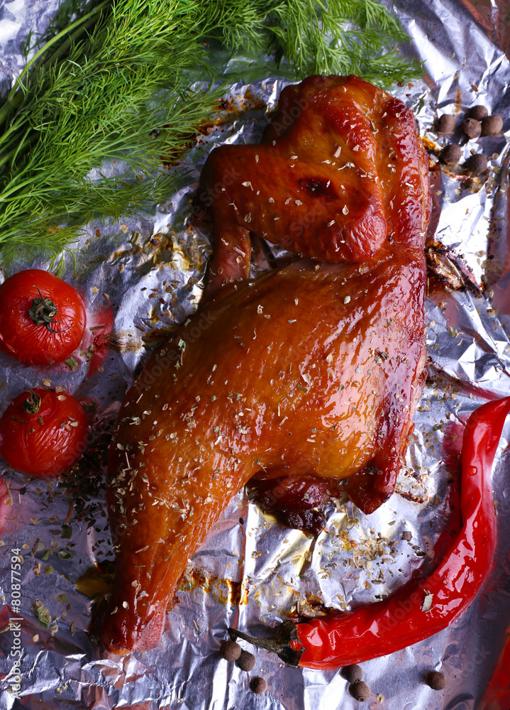 Sticker smoked chicken leg with cherry tomatoes on foil close up