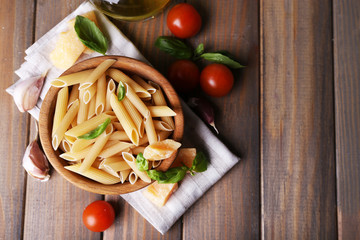 Raw pasta in bowl with cheese and vegetables on table close up