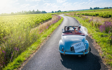 A newlywed couple is driving a retro car