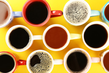 Many cups of coffee on color table, top view