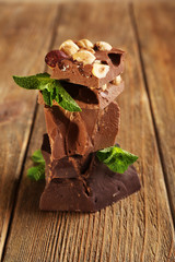 Stack of chocolate with nuts on wooden table, closeup