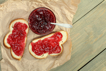 Toast with strawberry jam on a plate on a wooden background