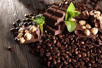 Chocolate with mint and coffee beans on wooden table, closeup