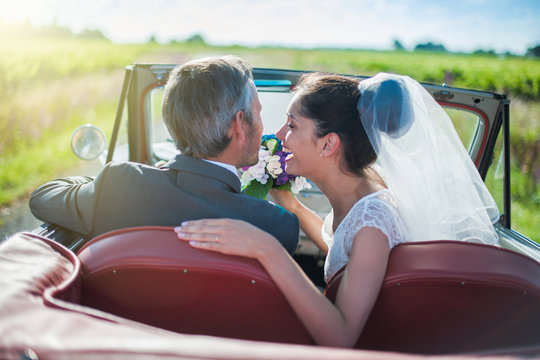 A newlywed couple is driving a retro car