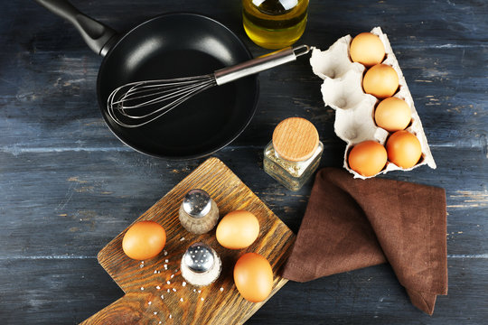 Still life with eggs and pan on wooden table, top view
