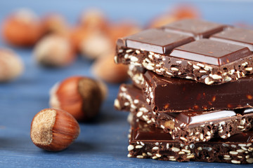 Pieces of chocolate with hazelnut on wooden table, closeup