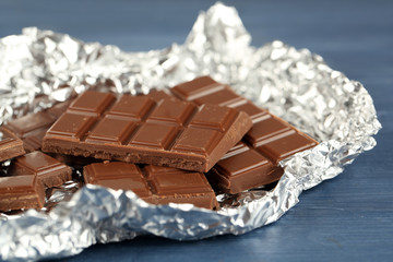 Chocolate in foil on wooden table, closeup