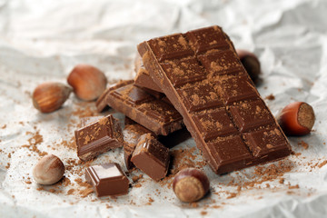 Pieces of chocolate with cocoa on parchment, closeup