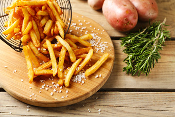 Tasty french fries in metal basket on wooden table background © Africa Studio