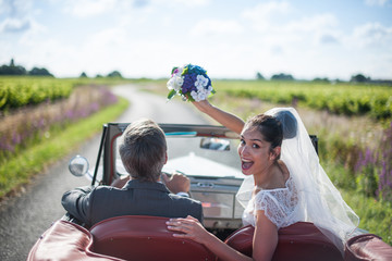 A newlywed couple is driving a retro car, rear view