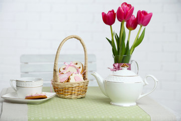 Tea set with flowers on table, on light background